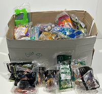 Over 50 sealed kids meal toys in original packaging displayed inside and in front of an open cardboard box. Various plastic toys from McDonald's, Burger King, and Wendy's visible.