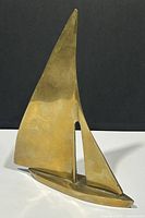 Full front view of brass mid century modern sailboat sculpture showing polished brass surface and stylized details.