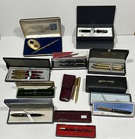 Full collection of 11 pen and pencil gift sets displayed on white surface