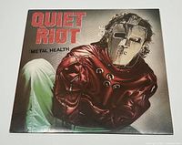 Front cover of Quiet Riot Metal Health album showing detailed artwork of figure in straitjacket and mask.