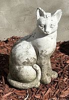 Front side view of the sitting cat concrete garden statue showing weathering and discoloration.