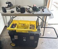 Full view of Stanley mobile tool chest with yellow compartment organizer and various small tools on top table.