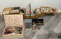 Wide view showing vintage accordion-style sewing basket fully opened with multiple compartments containing sewing notions and a separate Dritz handled sewing basket.