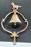 Front view of the vintage cast iron horse bell showing the overall shape, mounted horse figure, and hanging bell with rustic surface.