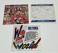 Three vintage charity 45rpm vinyl singles: Band Aid's "Do They Know It's Christmas?", USA for Africa's "We Are The World", and Northern Lights' "Tears Are Not Enough" with autographed cover.