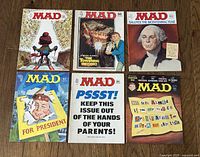 Photo showing all 6 Mad magazines from the 1970s laid out in two rows, covers visible including skier, The Towering Inferno, and George Washington bicentennial cover.