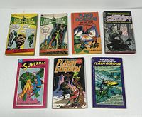 Seven vintage comic book paperbacks laid out in two rows featuring Green Lantern Green Arrow, Flash Gordon, Superman, and Creepy titles.