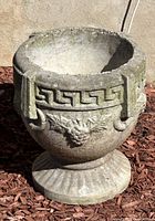Full view of the Grecian concrete garden planter showing the decorative relief and wear.