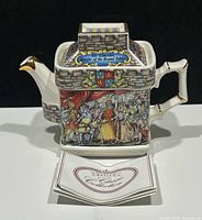 Front view of the square Sadler teapot showing detailed medieval scene and label on lid.