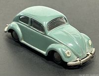 Front left angle view of the vintage Tekno die cast Volkswagen Beetle model showing intact bumper, windows, and body lines but missing right front headlight.