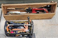 Two toolboxes: one wooden, one canvas, containing hand tools like caulking gun, wire strippers, hand saw, electrical tape.