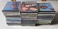 Stacks of approximately 50 jewel case compact discs showing titles like The Lettermen, The Turtles, and others.