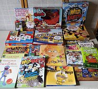 Top view of the full lot showing all board games and books in colorful packaging, arranged on a table.