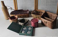 Seven woven baskets arranged on table, red container with lid, and green folder containing four pewter basket ornaments