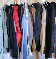 Side view of men's clothing hanging on rack including jackets, hoodies and shirts in various colors and sizes