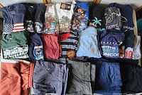 Top view of multiple men's t-shirts and pants folded and laid out showing variety of designs and colors