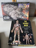 Box top showing Star Wars Millennium Falcon 3D Puzzle and The Visible Man anatomical model boxes stacked