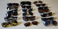 Overhead view of 15 assorted sunglasses showing variety of frame styles and lens colors, used to illustrate entire lot.