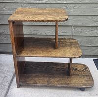 Front side view of the vintage 3 tier wooden end table showing the wood grain and rounded edges.