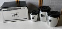 Photo of vintage West Bend metal bread box and three canisters with black lids showing the scale and condition of items.