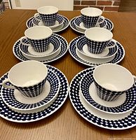 Six sets of Gustavsberg Adam bone china tea cups with matching saucers and plates arranged on a table, showing the blue dot pattern.