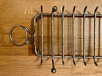 Silver plated toast rack lying on its side showing the circular handle and ten slots for toast slices.