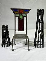 Miniature chair with stained glass detail in the backrest and metal seat and legs, shown with two metal twig-style candleholders.