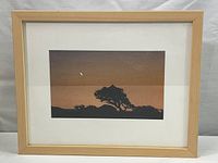 Framed print showing the silhouette of a tree and moon against an orange gradient sky, overall dimension about 15x12 inches.