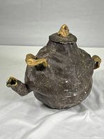 Front-right angled view of the hand made abstract brown and gold ceramic tea pot sculpture showing overall shape and color scheme.