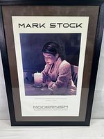 Framed Mark Stock artwork titled 'Languish' depicting a woman with a candle, with text and artist signature below.