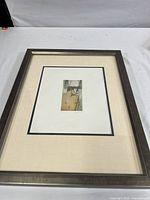 Framed artwork showing full piece with mat and frame on white surface.