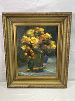 Full view of the framed oil painting depicting yellow and orange flowers in glass vases with small orange fruits on a surface.