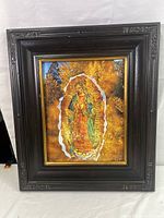 Full view of the framed print artwork of Our Lady, showing the worn dark wooden frame with carved details.
