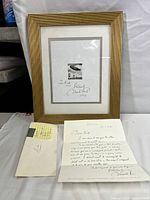 Framed signed artwork with letter and envelope displayed.