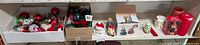 Wide view showing multiple boxes containing vintage glass Christmas bulbs, small festive figurines, and holiday decor on shelves.