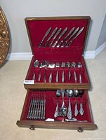 Full view of the velvet-lined wooden case containing the flatware set with multiple compartments holding knives, forks, spoons, and serving utensils.