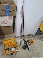 Fishing rods leaning against wall next to tackle box on garage floor, showing angling equipment and fishing rods.