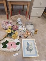 Photo showing entire group of floral themed decorative items including crochet purse, ceramic flowers, animal figurines, candle holder with red candles, and framed print.