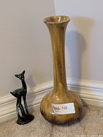 Tall Harvest Gold vase with narrow neck and bulbous base, and small green ceramic deer figurine beside it.
