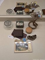Full view of lot items including Murano vase, wallet, clock, trinket dish, potpourri holder, and framed card shown on a countertop with a mirror reflecting items.