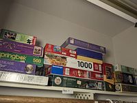 Top shelf view showing stacked boxes of puzzles including boxed Springbok 500-piece and several 1000-piece puzzles