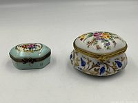 Two hand painted Limoges trinket boxes displayed side by side on white background, showing top and side details of each box.