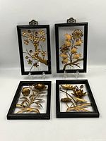 Four Mid Century 3D metal floral wall hangings displayed upright with black wood frames and gold flowers inside, shown from front view.