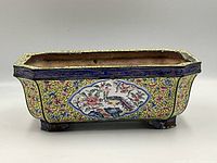 Side view of the planter showing floral and bird painted decoration and footed base