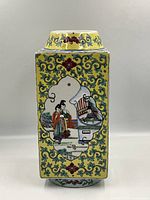 Front view showing rectangular vase with yellow background, detailed floral vine patterns, and painted figures in traditional Chinese attire within framed panels.