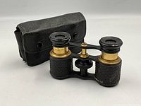 Opera binoculars shown from a side angle with case in background, highlighting leather wear on binoculars.
