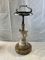 Full view of the antique standing ashtray showing the chrome top, carved marble base, and bird carving.