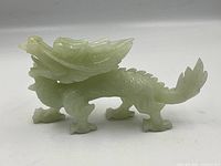 Side view of the jade dragon sculpture showing body, legs, wings, and tail details.