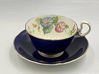 Side angle showing cup on saucer with cobalt blue exterior and floral pattern inside cup