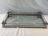 Full front view of chrome and mirror serving tray showing rectangular shape with tubular frame and mirrored bottom.